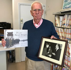 Skip Schumacher holds his copy of N is for Never Forget and a photo of himself receiving an award from actor John Wayne. Skip was on the USS Pueblo when it was seized by the North Koreans in 1968 and was held prisoner for 11 months.